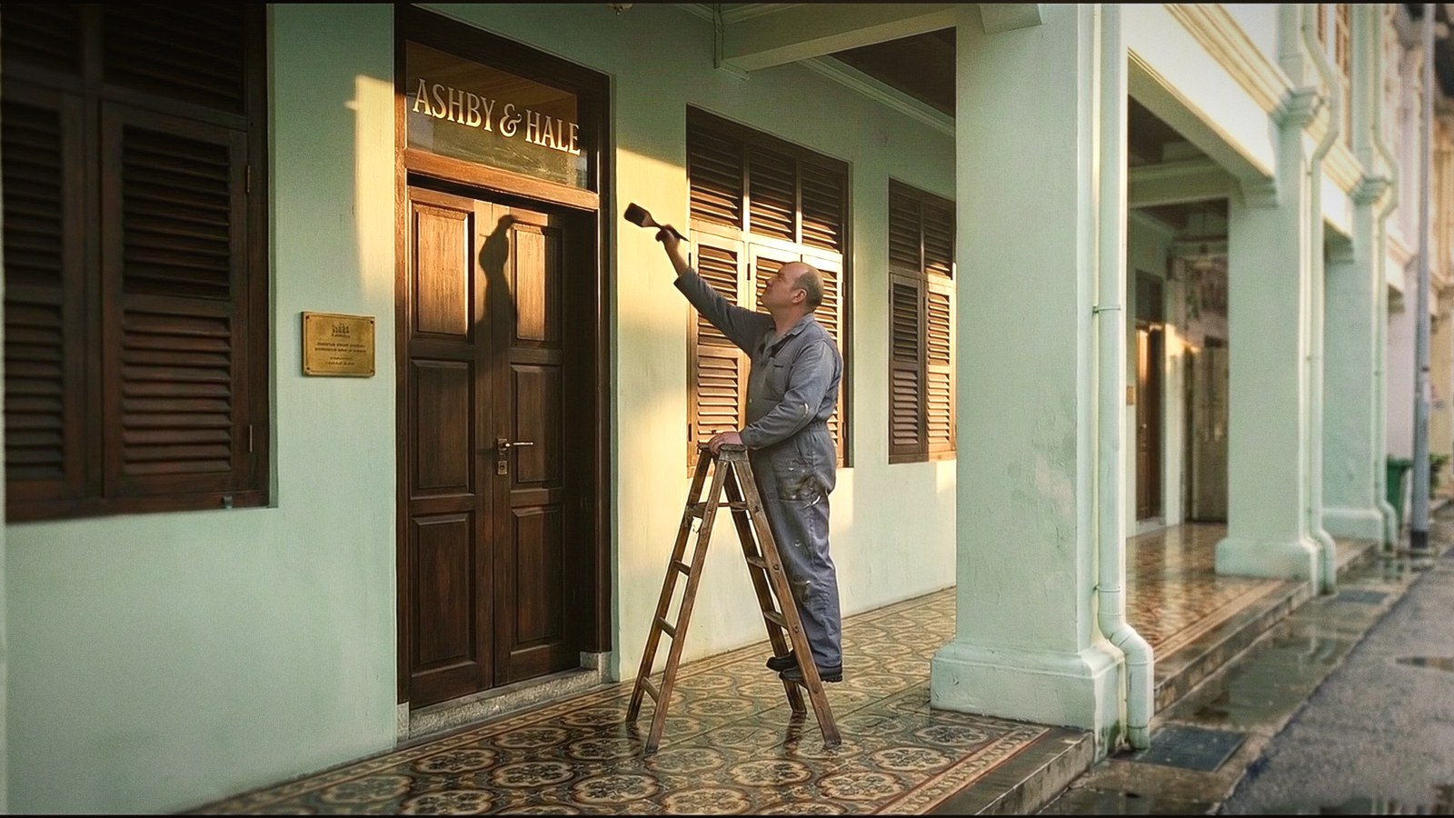 A sign painter gilding the firm’s name on the glass above the door